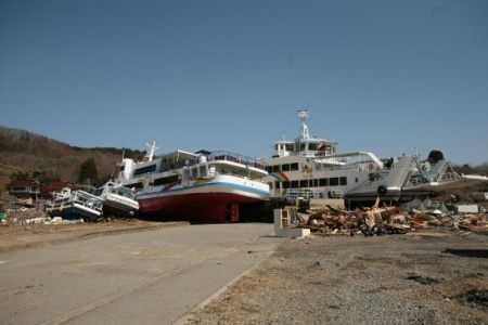 A boat is shown on land following a tsunami.