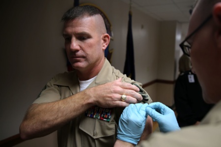 A flu shot is administered in this image.