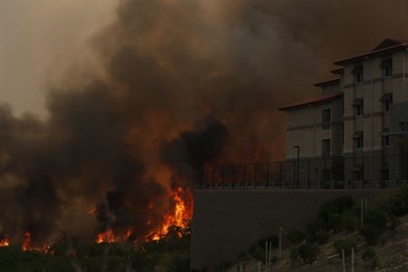A wildfire threatens a home in this image.