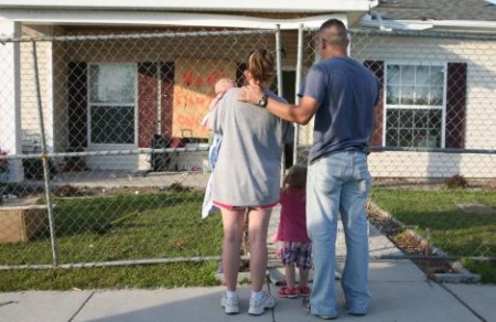 A family looks upon their home following a tornado in this image.