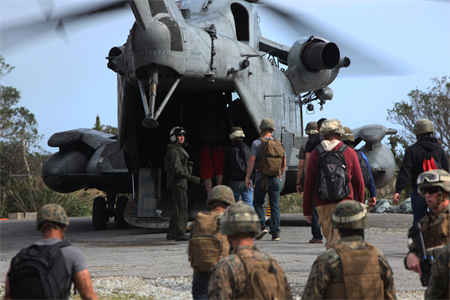 Marines assist noncombatants board an aircraft during an evacuation.